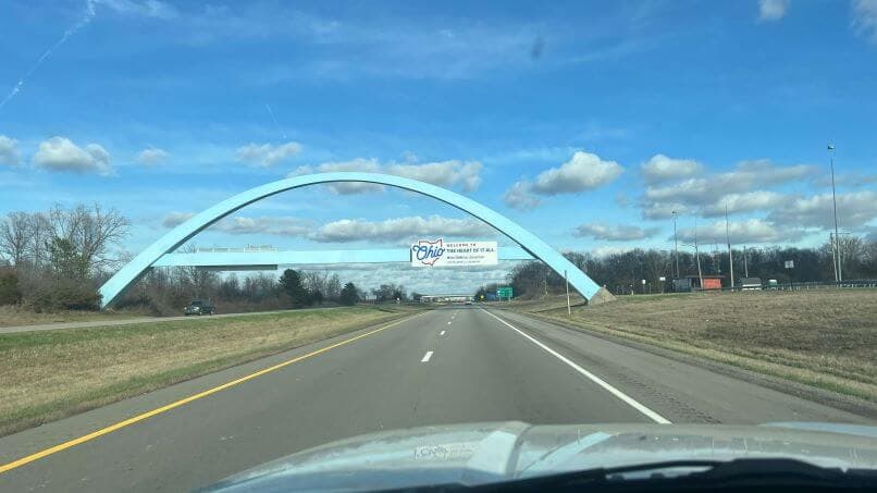 Welcome to Ohio sign on a bridge overpass viewed from the dashboard of a car